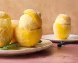 Sorbetto al limone senza albume servito in scorze di limone ghiacciate, guarnito con foglioline di menta e mirtilli.