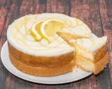 Torta al limone soffice e profumata, con glassa bianca e decorazioni gialle, guarnita con fette di limone.