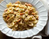 Farfalle cremose con salmone affumicato, un piatto gustoso e invitante, guarnito con prezzemolo fresco e pepe nero.