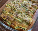 Involtini di zucchine grigliate al forno, dorati e croccanti, in una pirofila di vetro.