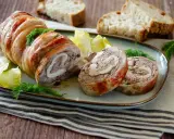 Coniglio in porchetta, un rotolo di carne succulento con erbe aromatiche, servito con pane tostato e insalata.