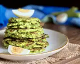 Pila di rosti di zucchine dorati, guarnita con spicchi di uovo sodo. Un piatto leggero e gustoso, perfetto per ogni pasto.