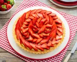 Deliziosa crostata di fragole con crema pasticcera, decorata con fragole fresche affettate. Un dolce estivo perfetto.