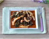 Un saporito piatto di seppie in zimino, con verdure scure e salsa rossa, servito su un tovagliolo a quadretti verdi.