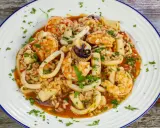 Un invitante risotto alla pescatora, ricco di gamberi, calamari e cozze, guarnito con prezzemolo fresco.