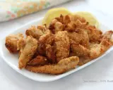 Straccetti di pollo in friggitrice ad aria, dorati e croccanti, serviti con spicchi di limone.