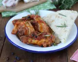 Piatto di friccò di pollo succulento con rosmarino e pane rustico su un piatto smaltato.