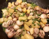 Un gustoso piatto di seppie e patate, con piselli verdi sparsi, condito con erbe aromatiche.