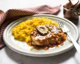 Un succulento ossobuco alla milanese, con il suo midollo invitante, adagiato su un letto di risotto giallo zafferano.