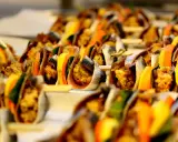 Sarde a beccafico su spiedini, con fette d'arancia e limone, un antipasto siciliano colorato e invitante.