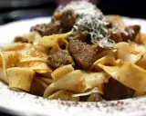 Pappardelle al cinghiale, un piatto ricco e saporito con pasta fresca e ragù di cinghiale, spolverato di parmigiano.