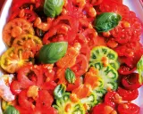 Un'insalata di pomodori colorati, affettati e conditi con erbe aromatiche fresche.