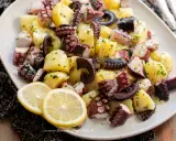 Un invitante polpo con patate, condito con prezzemolo e servito con spicchi di limone.