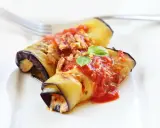 Deliziosi involtini di melanzane ripieni, conditi con sugo di pomodoro e basilico fresco, pronti per essere gustati.