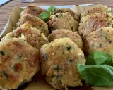 Deliziose polpette di zucchine grattugiate in padella, dorate e croccanti, guarnite con foglie di basilico fresco.