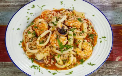 Un invitante risotto alla pescatora, ricco di gamberi, calamari e cozze, guarnito con prezzemolo fresco.