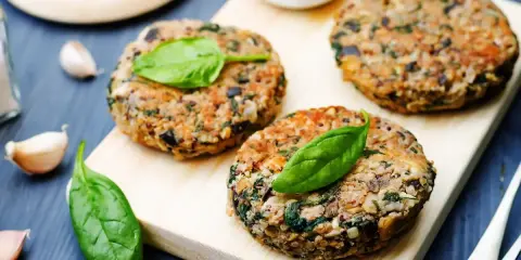 Hamburger di melanzane fatti in casa, guarniti con foglie di spinaci freschi, pronti per essere gustati.