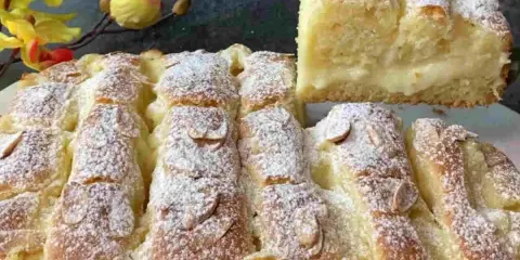 Torta al limone velocissima, soffice e profumata, cosparsa di zucchero a velo e mandorle. Una fetta mostra il ripieno cremoso.
