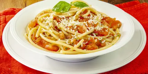 Un piatto di pasta alla carrettiera fumante, con pomodoro fresco, basilico e abbondante formaggio grattugiato.