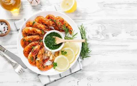 Gamberoni succulenti cotti nella friggitrice ad aria, serviti con salsa verde, limone e rosmarino.