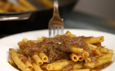 Un piatto invitante di ziti alla genovese, con la pasta condita da un ricco ragù di carne e cipolle.