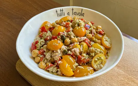 Insalata di tonno con pomodorini gialli, ceci e peperoni rossi, condita con un pesto leggero. Perfetta per un pasto fresco e gustoso.