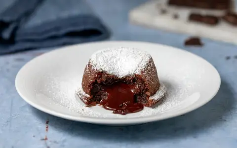 Un tortino al cioccolato con cuore fuso, spolverato di zucchero a velo. Perfetto per dolci morbidi e veloci da preparare.
