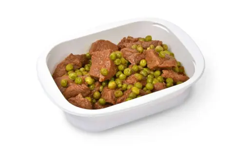 Un saporito spezzatino con piselli in una ciotola bianca, pronto per essere gustato.