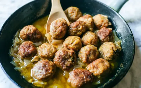 Polpette di carne morbide in padella, dorate e succulente, cuociono in un sughetto saporito con cipolle.