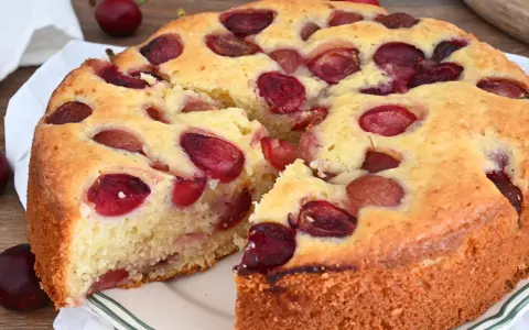 Una deliziosa torta alle ciliegie, con la crosta dorata e tante ciliegie rosse immerse nell'impasto soffice.