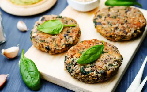 Hamburger di melanzane fatti in casa, guarniti con foglie di spinaci freschi, pronti per essere gustati.