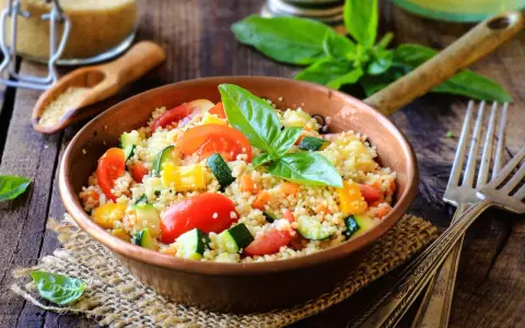 Un piatto colorato con cous cous, pomodori, zucchine e peperoni, perfetto per una ricetta cous cous originale e fresca.