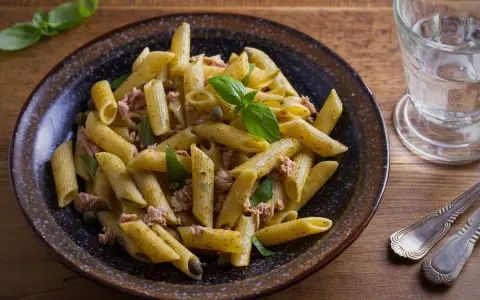 Penne al pesto con tonno, capperi e basilico fresco, un piatto gustoso e veloce.