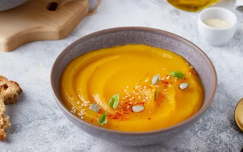 Vellutata di zucca cremosa, guarnita con semi di zucca, sesamo e basilico. Accompagnata da crostini dorati.