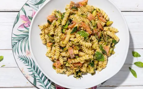 Fusilli con salmone e zucchine, un piatto fresco e colorato, guarnito con basilico.