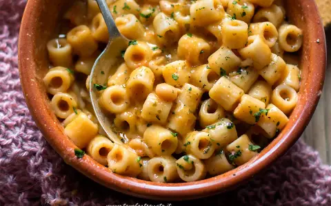 Un piatto fumante di pasta e fagioli, con ditalini e fagioli bianchi in un sugo cremoso, guarnito con prezzemolo tritato.