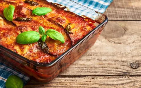 Parmigiana di melanzane in friggitrice ad aria, dorata e profumata, guarnita con basilico fresco. Un piatto gustoso e leggero.