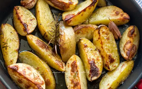 Patate al forno croccanti, dorate e profumate al rosmarino e aglio, pronte per essere gustate.