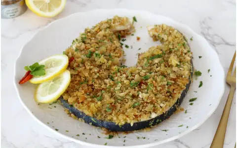 Un invitante pesce spada alla palermitana, dorato e croccante, guarnito con limone e peperoncino.
