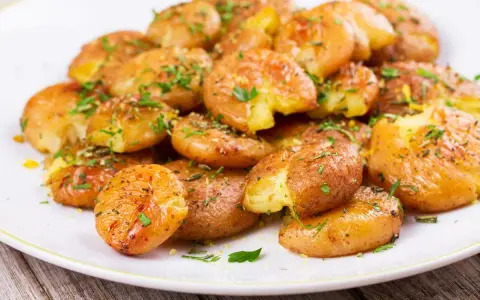 Patate lesse in friggitrice ad aria, croccanti e dorate, condite con erbe aromatiche fresche.