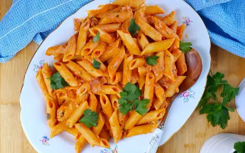 Penne al baffo cremose e saporite, guarnite con prezzemolo fresco, servite su un piatto elegante.