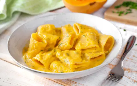 Piatto di pasta e zucca cremoso, con un tocco di erbe aromatiche. Un comfort food autunnale da gustare.