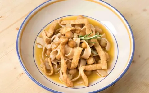 Piatto di ciceri e tria, pasta fresca con ceci e croccanti straccetti fritti, guarnito con rosmarino.