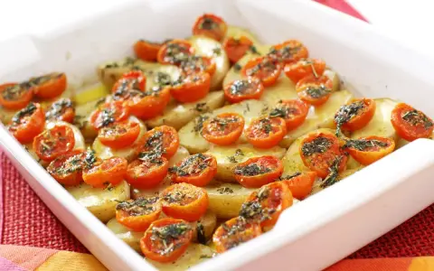 Parmigiana di patate al forno con pomodorini e erbe aromatiche, un piatto semplice e gustoso.