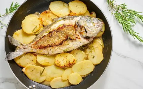 Orata in padella con patate e rosmarino, un piatto succulento e profumato, pronto per essere gustato.
