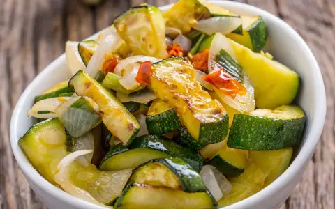 Zucchine in padella, dorate e saporite, con cipolla e pomodoro. Un contorno leggero e gustoso.