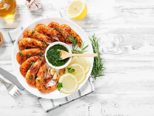 Gamberoni succulenti cotti nella friggitrice ad aria, serviti con salsa verde, limone e rosmarino.