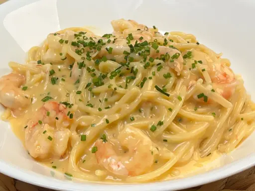Spaghetti cremosi con gamberi e erba cipollina, una deliziosa carbonara di pesce.