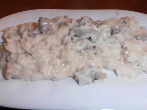 Un cremoso risotto con salsiccia, servito su un piatto bianco.