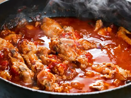 Carne alla pizzaiola morbida che sobbolle in padella, con pomodoro e profumi invitanti.